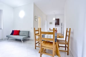 Een moderne woonkamer met een bank, een eettafel, stoelen en een kapstok.