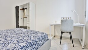 A bedroom with a bed, a desk, a chair, a wardrobe, and a mirror.