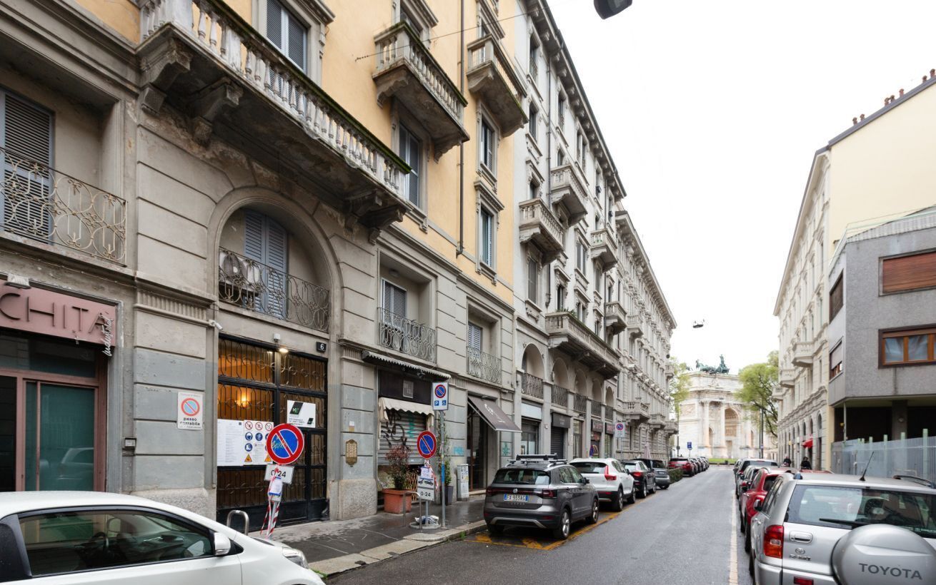 Une rue bordée de bâtiments historiques, de voitures garées et d’un panneau indiquant qu’il est interdit de se garer.