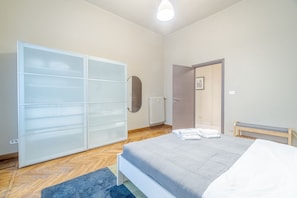 Una camera da letto con un letto, un armadio, un termosifone e una panca.
