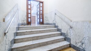 Una escalera de mármol con una puerta de madera al final, que conduce a un piso superior.