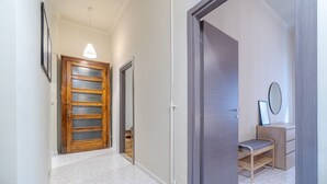 Un pasillo con una puerta de madera, un banco y una mesita con un espejo.