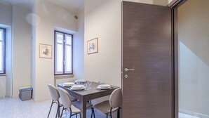 Un comedor con una mesa dispuesta para cuatro personas, una puerta y dos ventanas.