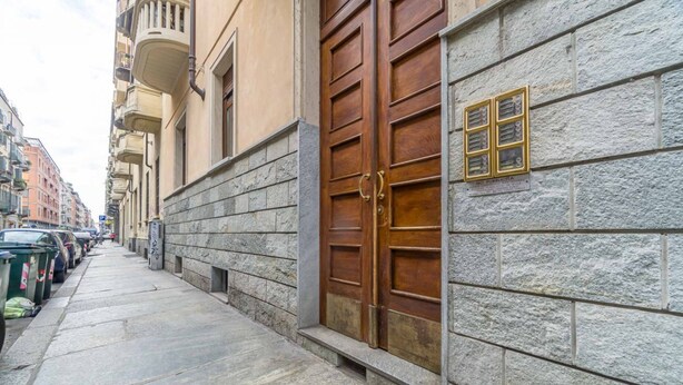 Un edificio de piedra con una puerta de madera grande y una pequeña ventana con un letrero.