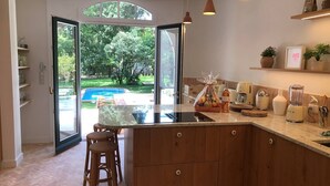 Una cocina con una isla grande, armarios de madera y vistas a un patio trasero con piscina.