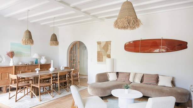 Una sala de estar moderna con una mesa de comedor de madera, sillas blancas, un sofá beige y una mesa de centro redonda.