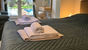 Una cama bien hecha con una colcha verde acolchada y dos toallas enrolladas.