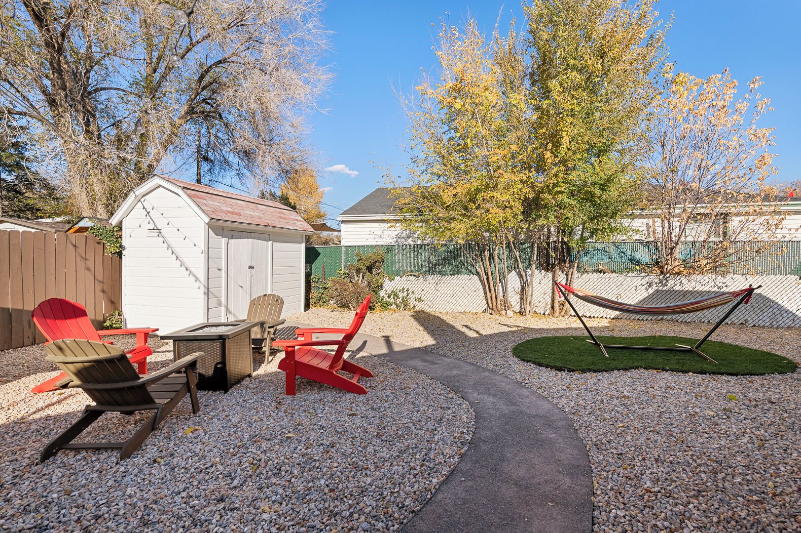 A backyard with a gravel path, a hammock, and outdoor furniture.