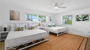 A bedroom with two beds, a ceiling fan, and large windows. - Beautiful Lakeside Oasis (West Palm Beach)
