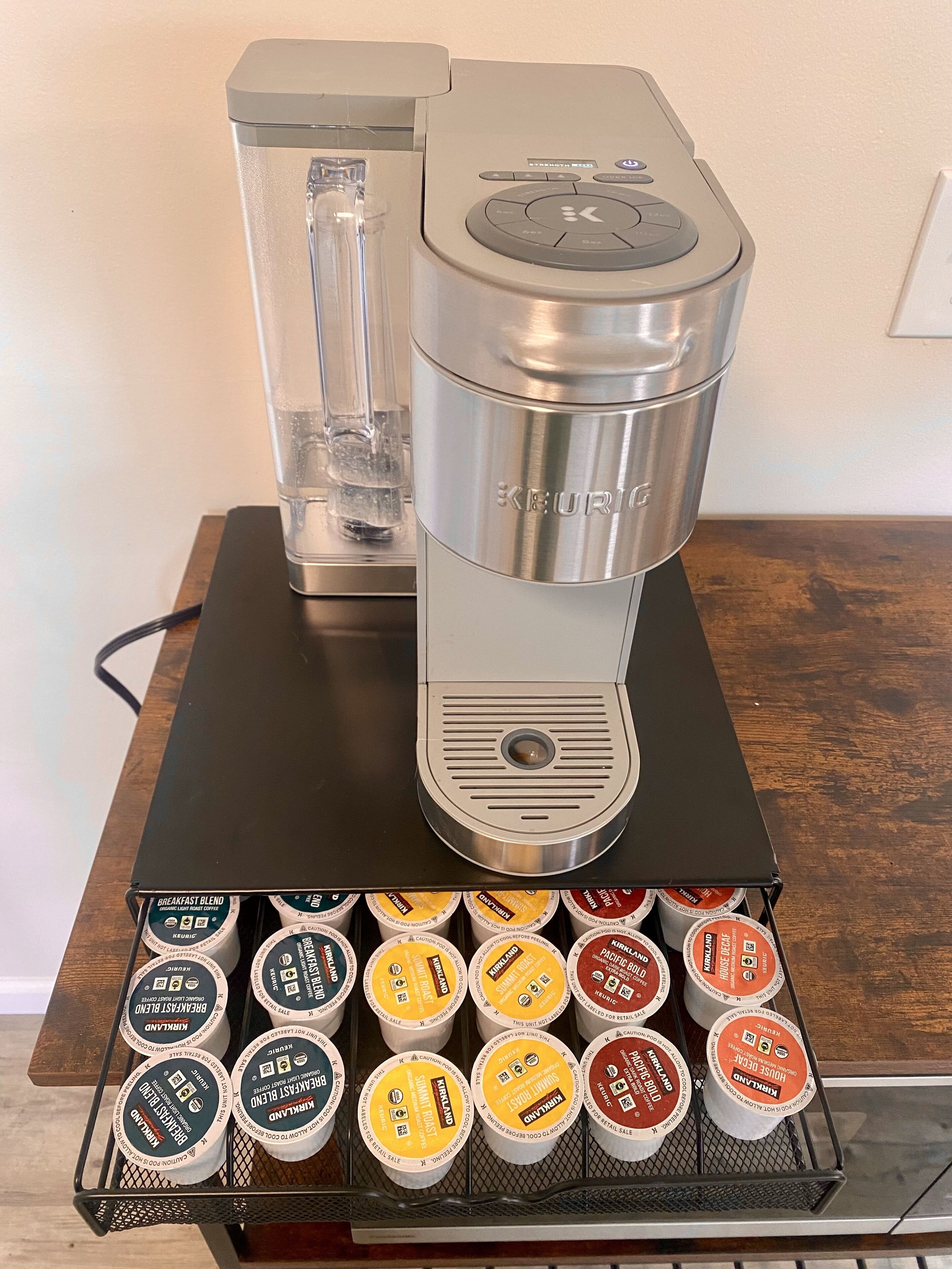 Een Keurig koffieapparaat met een waterreservoir en een houder voor koffiekapsules eronder.