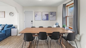 Una sala de estar moderna con un sofá azul, una mesa de comedor de madera con sillas negras y un purificador de aire blanco.