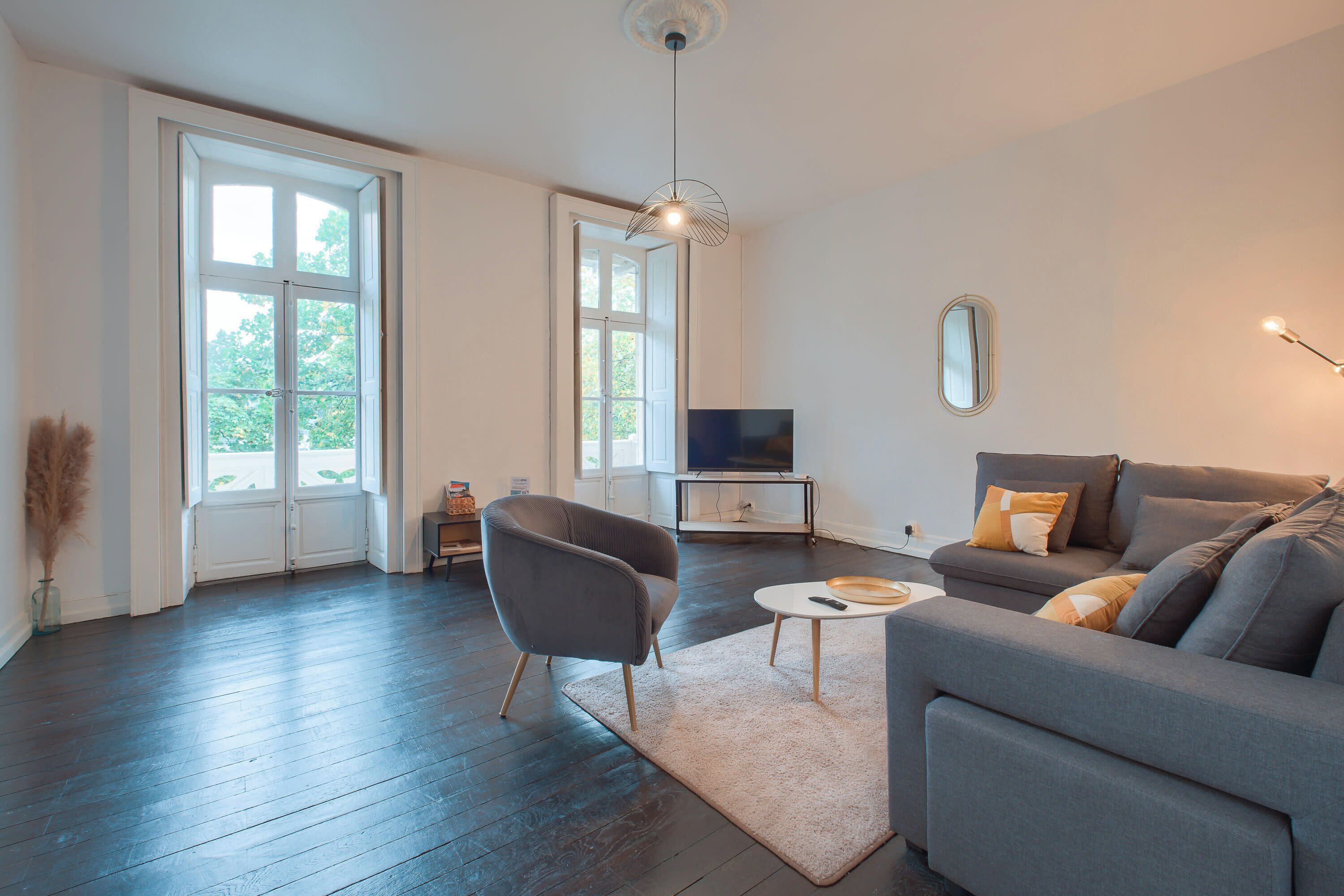 A modern living room with a grey sofa, a small round table, and a television.