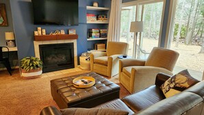 Una sala de estar con chimenea, televisor y vista al exterior.