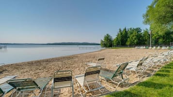 A beach with rows of metal chairs and a grassy area.