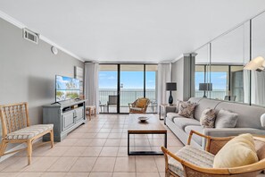 Un salon moderne avec un canapé, des fauteuils, une table basse et un téléviseur.