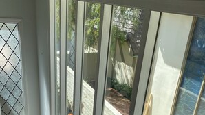 Un escalier menant à un balcon d’où l’on peut admirer un jardin, avec un pot bleu posé sur la balustrade.