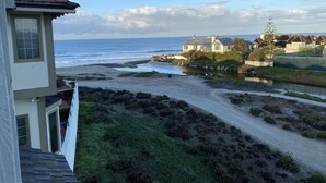 Une vue côtière avec une plage de sable, une rivière et des maisons donnant sur l’océan.