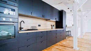 A modern kitchen with dark cabinetry, wooden countertops, and a built-in oven. - Sublime Loft à St Germain (6pax) (Paris)