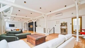 A spacious living area with a white sofa, a wooden coffee table, and a green armchair. - Sublime Loft à St Germain (6pax) (Paris)
