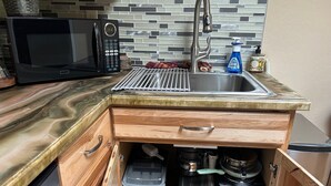 Cozinha compacta com micro-ondas, torradeira e pia.