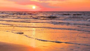 A sunset over the ocean with waves on the shore. - RV8 | Family Beach Getaway - Luxury Sabre (Bolivar Peninsula)