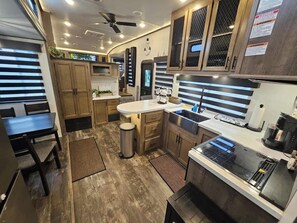 A compact kitchen with wooden cabinets, a central island, a sink, and a stove. - RV8 | Family Beach Getaway - Luxury Sabre (Bolivar Peninsula)