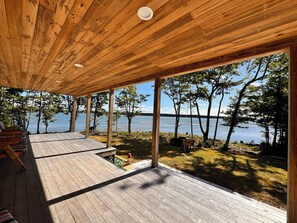 A wooden deck with outdoor seating and a view of a lake.