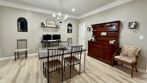 Un coin repas avec une table et des chaises en bois, un lustre et un buffet en bois agrémenté d’objets décoratifs.