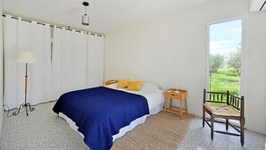 A bedroom with a bed, a bedside table, a chair, a lamp, and a view of greenery outside. - Nice home in Saint-Maximin (Saint-Maximin)
