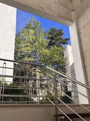 A staircase with metal railings leading to a building with stone walls and a tree in the background.