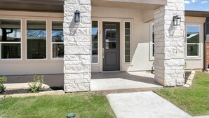 Une maison avec une façade en pierre, une porte d’entrée et deux fenêtres.