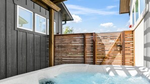 Un jacuzzi dans un jardin, avec une clôture en bois et une maison en arrière-plan.