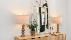 Une console en bois, agrémentée de deux lampes, d’un miroir et d’objets décoratifs.