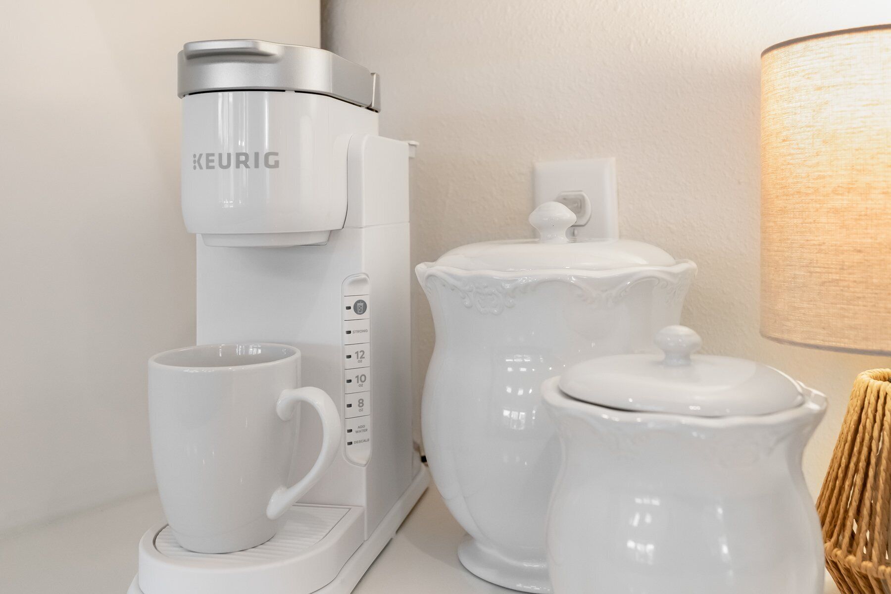 A coffee maker, a mug, and a sugar container on a countertop.