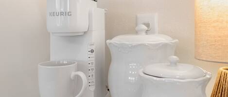 A coffee maker, a mug, and a sugar container on a countertop.