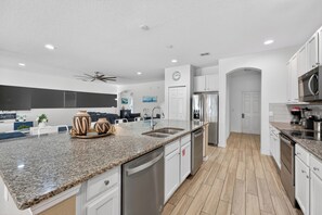 A modern kitchen with granite countertops, stainless steel appliances, and white cabinetry.