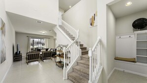 A spacious living area with a staircase, a dining area, and a view of the outdoors.