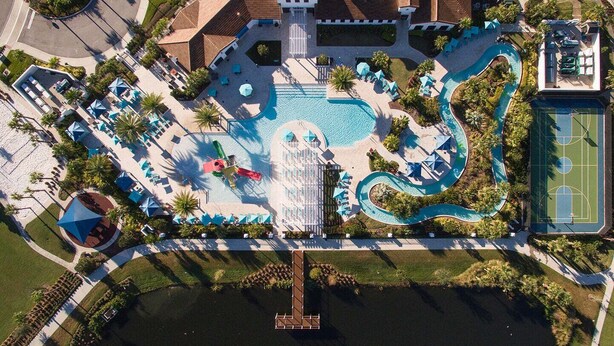 An aerial view of a resort with a swimming pool, tennis court, and a dock.