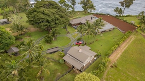 An aerial view of a residential area with houses, a road, and a body of water in the background.