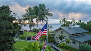 A house with a flagpole, a pathway, and a view of the ocean.