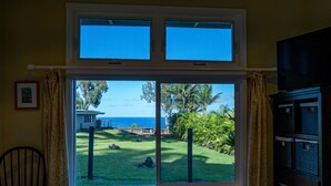 A room with a large window overlooking a grassy area with palm trees and a view of the ocean.