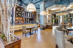 A modern bar area with a wooden bar counter, seating, and pendant lighting.