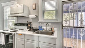 A kitchen with white cabinets, a stove, a sink, and a window with blinds. - Norfolk Apartment: 1 Mi to Ocean View Beach Park! (Norfolk)