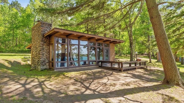 A stone cabin with large windows, a wooden deck, and a forested backdrop. - Cabin 2 at Timberlane Resort on Long Lake (Park Rapids, MN)