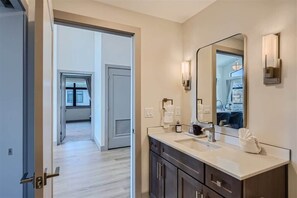 A modern bathroom with a large mirror, dark cabinets, and a light-colored countertop.