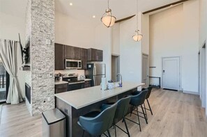 A modern kitchen with dark cabinets, a central island with bar stools, and pendant lighting.