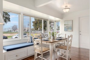 A dining area with a large window, a bench, and a table set for four.