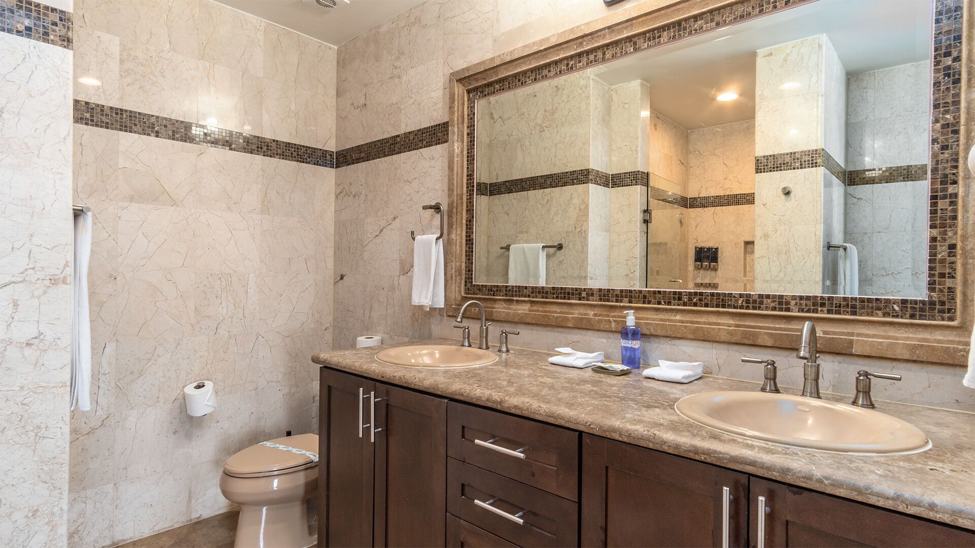 Un baño con dos lavamanos, un espejo grande y un inodoro.