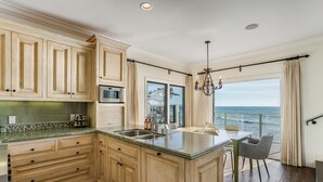 A kitchen with a large island, a dining area with a view, and a chandelier. - Luxury, renovated, oceanfront home with incredible deck & ocean views - dog friendly! (La Jolla)