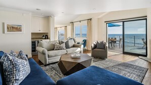 A spacious living area with a sofa, coffee table, and a view of the sea through large windows. - Luxury, renovated, oceanfront home with incredible deck & ocean views - dog friendly! (La Jolla)